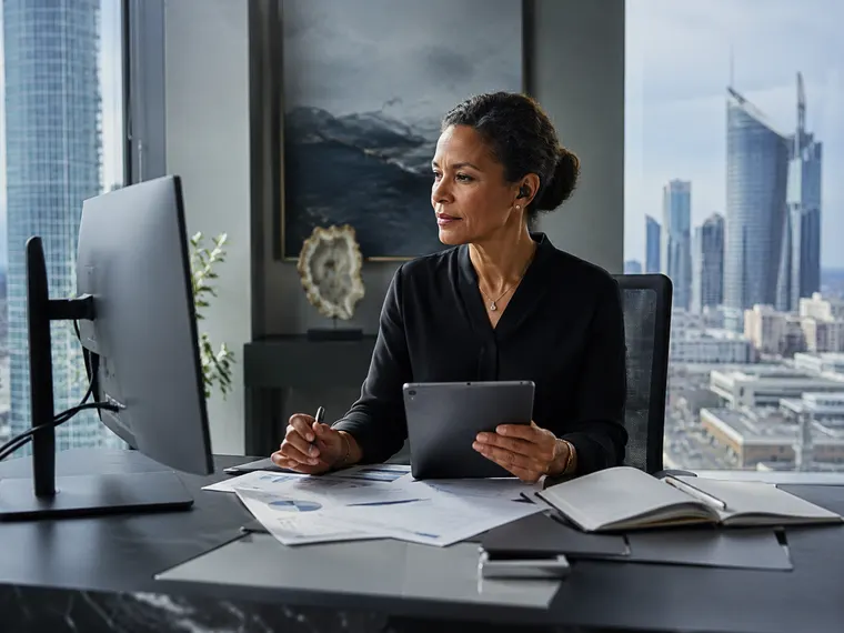 A professional reviewing figures on a tablet in a high-rise city office